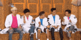 a group of young men are sitting on a bench and one of them has a shirt that says ' a ' on it