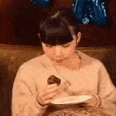 a woman is sitting on a couch eating a piece of cake with a fork .