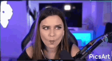 a woman wearing headphones is sitting in front of a microphone in a purple room .