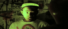 a boy wearing a hat that says fmr on it stands in front of a wall with graffiti on it