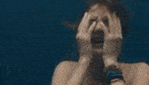 a woman is swimming underwater with her eyes closed and a sad look on her face .