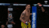 a man in a yellow ufc shorts is standing in front of a cage