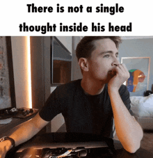 a man is sitting at a desk with his hand on his chin and a meme that says there is not a single thought inside his head