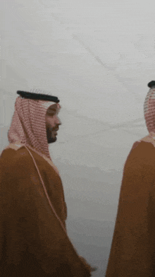 two men in traditional arabic clothing are standing next to each other in the fog