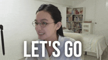 a woman wearing glasses says let 's go in a bedroom