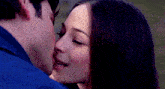 a man and a woman are kissing in a close up of their faces .