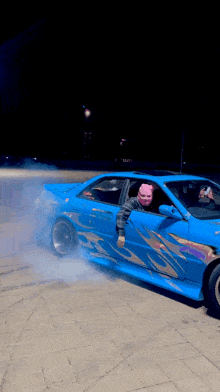 a man in a pink mask is sitting in a blue car
