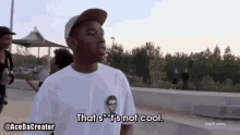 a man wearing a hat and a white shirt is standing on a sidewalk and says `` that 's not cool ''