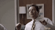 a man in a white shirt and tie is dancing in a room with a lamp .