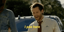 a man in a tie says i pee here in front of a car