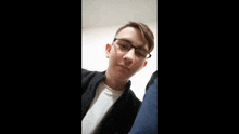 a young man wearing glasses and a white shirt is making a funny face