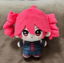 a stuffed doll with pink hair is wearing a blue outfit