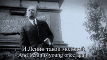 a man stands in front of a sign that says " and lenin is young once again " on it