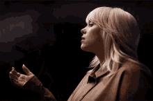 a woman is holding something in her hands in a dark room and looking up at the sky .