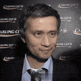 a man stands in front of a wall that says carling cup on it