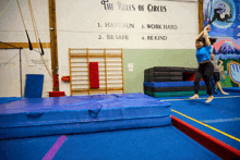 the rules of circus are displayed on a wall behind a gymnast