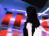 a woman with long black hair stands in a room with chinese writing