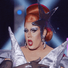 a drag queen is wearing a star shaped costume and earrings