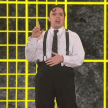 a man in a white shirt and black pants is standing in front of a yellow grid