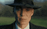 a man wearing a hat and a suit looks at the camera