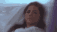 a woman is laying in a hospital bed with a purple blanket .
