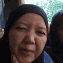 a woman in a hijab is making a funny face while looking at the camera .