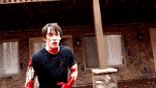a man with blood on his face and hands stands in front of a stone wall