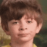 a close up of a young boy 's face with a yellow shirt on .
