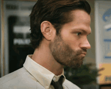a man with a beard wears a white shirt and a black tie
