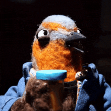 a stuffed bird is holding a blue bottle in its beak