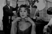 a black and white photo of a woman singing in front of a microphone in a band .