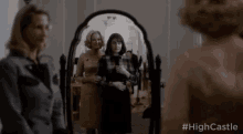 two women are standing in front of a mirror and looking at themselves .