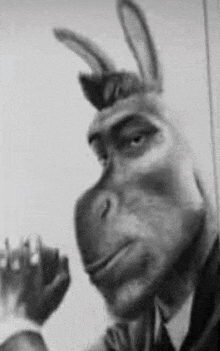 a black and white photo of a man in a suit and tie with a donkey mask on his face .