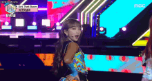 a woman is standing on a stage in front of a colorful backdrop .