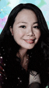 a woman with long black hair is smiling in front of a blue background