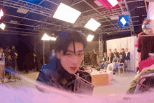 a blurry photo of a man in a room with a group of people behind him