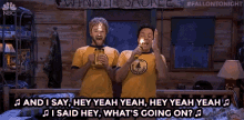 a couple of people standing next to each other holding candles and singing a song