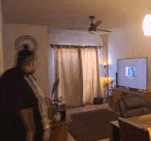 a man stands in a living room watching a television