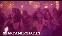 a group of people are dancing in a dark room and the website starttamilchat.in is visible