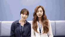 two women are sitting next to each other with their eyes closed and one has a lanyard with the letter l on it