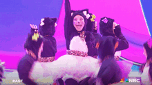 a group of people dressed in cat costumes on a stage with the nbc logo