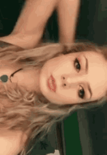 a close up of a woman 's face with a necklace around her neck .