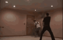 two men are fighting in a room with a door in the background
