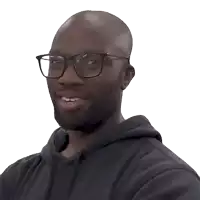 a bald man wearing glasses and a black hoodie is smiling