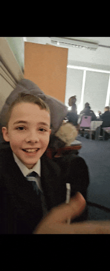 a young boy in a suit and tie is smiling in a room