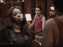 a man and a woman are fighting in a room with a group of people .