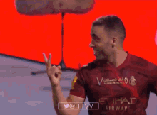 a man in a red etihad airways shirt holds up his finger