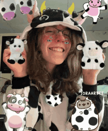 a girl in a cow costume is holding stuffed cows in her hands
