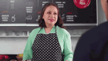 a woman in a polka dot apron stands in front of a chalkboard that says cafe on it