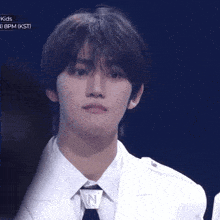 a young man in a white suit and tie is looking at the camera